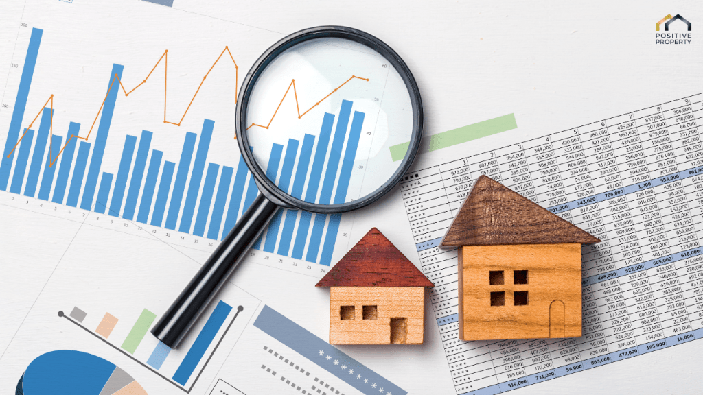 Magnifying glass analysing property data charts with miniature wooden houses, symbolising strategic real estate investing.
